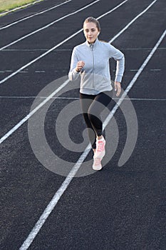 Runner athlete running on athletic track training her cardio in stadium. Jogging at fast pace for competition