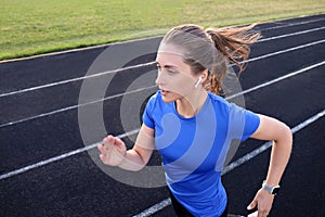 Runner athlete running on athletic track training her cardio in stadium. Jogging at fast pace for competition