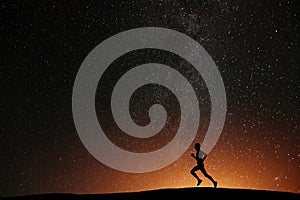 Runner athlete running on the hill with beautiful starry night photo