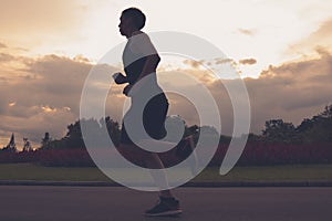 Runner athlete silhouette running in public park. man fitness sunrise jogging workout wellness concept