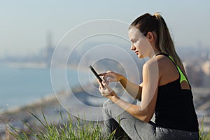 Runner checking smart phone in city outskirts after sport