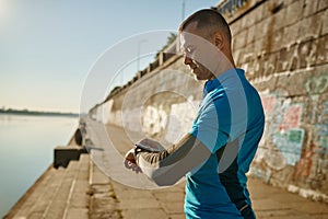 Runner checking smartwatch controlling pulsations after exercise