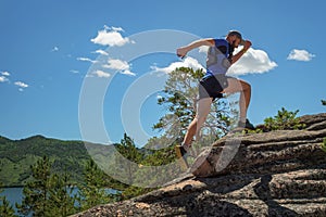 Runner Climbing a Rock. The athlete runs on the rocks in the mountains. Outdoor trail running