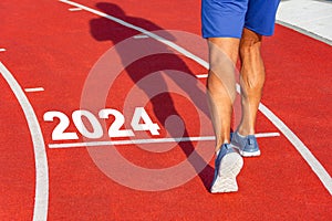 Runner crosses the line starting in 2024 on a red treadmill with the numbers 2024. New year entry concept, step.