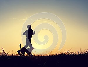Runner and dog silhouttes in sunset light photo