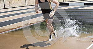 Runner exiting the water of the steeplechase during a track race