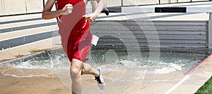 Runner exiting the water at the steeplechase water jump during a race