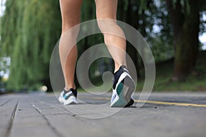 Runner feet running on road closeup on shoe, outdoor at sunset or sunrise