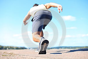 Runner feet running on road closeup on shoe, outdoor at sunset or sunrise