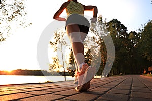 Runner feet running on road closeup on shoe, outdoor at sunset or sunrise