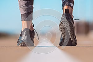 Runner feet running on road closeup on shoe. Woman exercising outdoors. Healthy lifestyle, workout, wellness concept