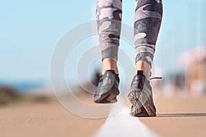 Runner feet running on road closeup on shoe. Woman exercising outdoors. Healthy lifestyle, workout, wellness concept
