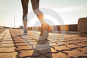 Runner feet running on road closeup on shoe. woman fitness sunrise jog workout welness concept.