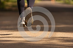 Runner feet running on road closeup on shoe. woman fitness sunrise jog workout welness concept.