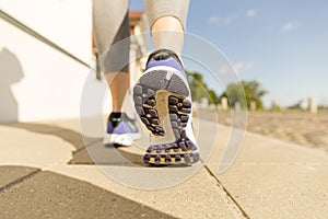 Runner feet running on road closeup on shoe. woman fitness sunrise jog workout welness concept