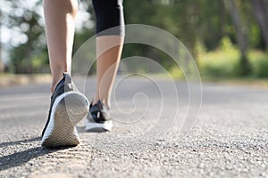 Runner feet running on road closeup on shoe. Woman fitness sunrise jog workout welness concept. Young fitness woman runner athlete