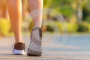 Runner feet running on the road in the outdoor workout park, closeup on shoe. Asian fitness woman running for healthy and relax.