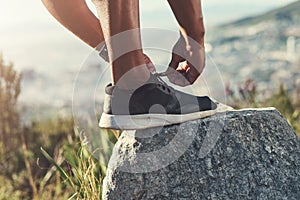 Runner, foot and tying laces on rock, outdoors and prepare for cardio and marathon training. Man, stone and shoe for