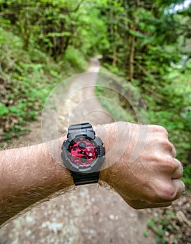 Runner on forest trail looking at wearable sportwatch