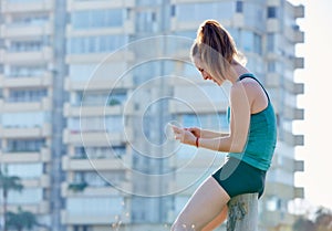 Runner girl having a rest and using smartphone