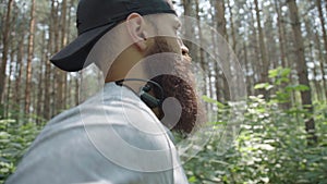 Runner with headphones, profile. A man with a beard and a cap