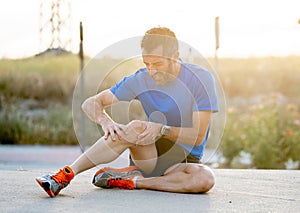 Runner holding his knee in pain after pulling a muscle.