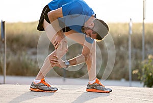 Runner holding his knee in pain after pulling a muscle.