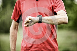 Runner looking at sport or smart watch checking pulse or gps