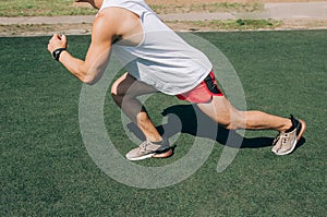 Runner man getting ready to run doing warm-up dynamic leg stretch exercises routine.