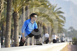 Runner man stretching at beach palm trees boulevard with sunglasses in morning jog training session