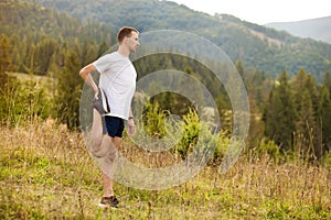 Runner man stretching legs before cross country trail run. Fit male runner exercise training outdoors