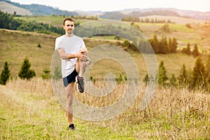 Runner man stretching legs before cross country trail run. Fit male runner exercise training outdoors