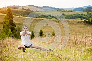 Runner man stretching legs before cross country trail run. Fit male runner exercise training outdoors in mountain