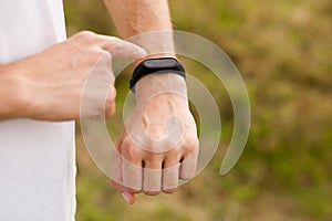 Runner on mountain trail looking at sports smart watch, checking performance or heart rate pulse trace.