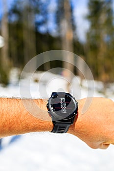 Runner on mountain trail looking at stopwatch, activity tracker