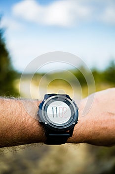 Runner on mountain trail looking at stopwatch, activity tracker