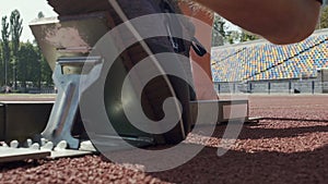 Runner putting his feet on footplates of starting blocks and runs after command