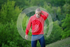 Runner in red jacket with a hood and black sport leggins rest a