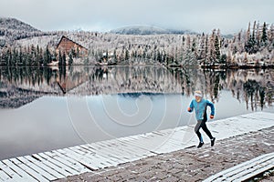 Runner run by the lake in white winter nature