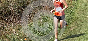 Runner running on a grass field downhill during a cross country 5K race