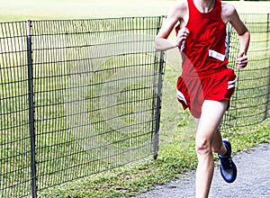 Runner running next to a wire fence during high school cross country race