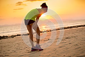 runner with sports injured leg running at sunset sandy beach