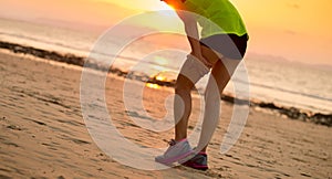 runner with sports injured leg running at sunset sandy beach