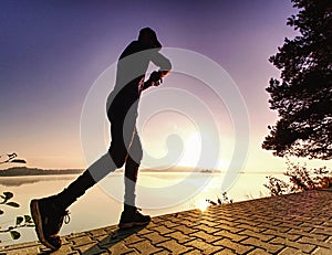 Runner sprints along lake. Freeze sportsman in running pose