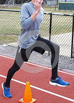 Runner stepping over orange cone on a red track