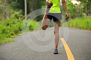 Runner stretching legs before running at morning tropical forest trail