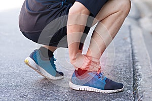 Runner touching painful twisted or broken ankle. Athlete runner training accident. Sport running ankle sprain. photo