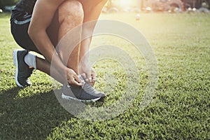runner tying shoelace on grass at park