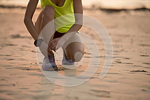runner tying shoelace before run on sunset beach