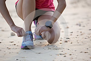 runner tying shoelace before running on sandy beach